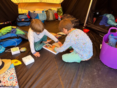 Very young children playing with games in a tent at Abercastle Campsite